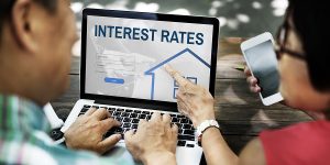 a couple looks at interest rates online to determine if they should refinance their mortgage